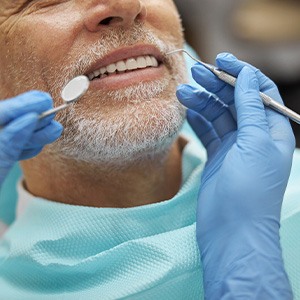 Nose-to-shoulder view of man with white facial hair about to have dental exam