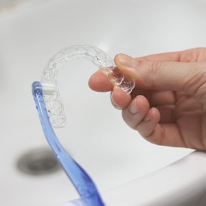 Patient cleaning clear aligner in sink