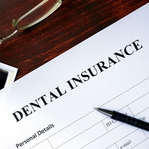 Top of dental insurance form with pen, glasses, and X-ray of teeth