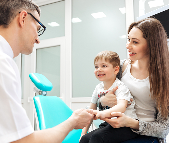 Toddler boy in his mothers lap visiting the dentist