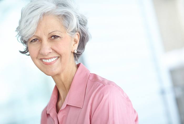 Woman with gray hair in pink shirt smiling