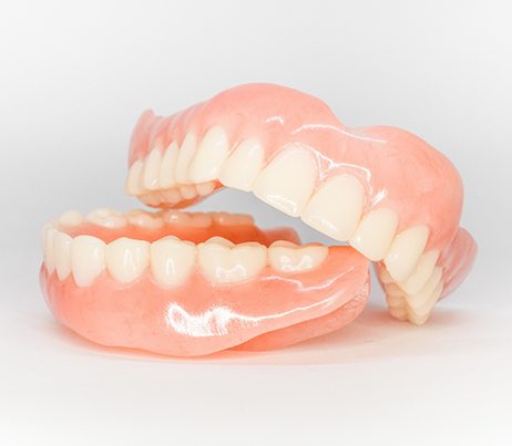 Full set of dentures glistening on white surface