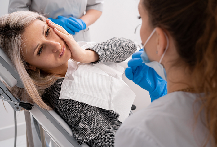 Woman holding her cheek in pain while talking to emergency dentist in Salmon Creek