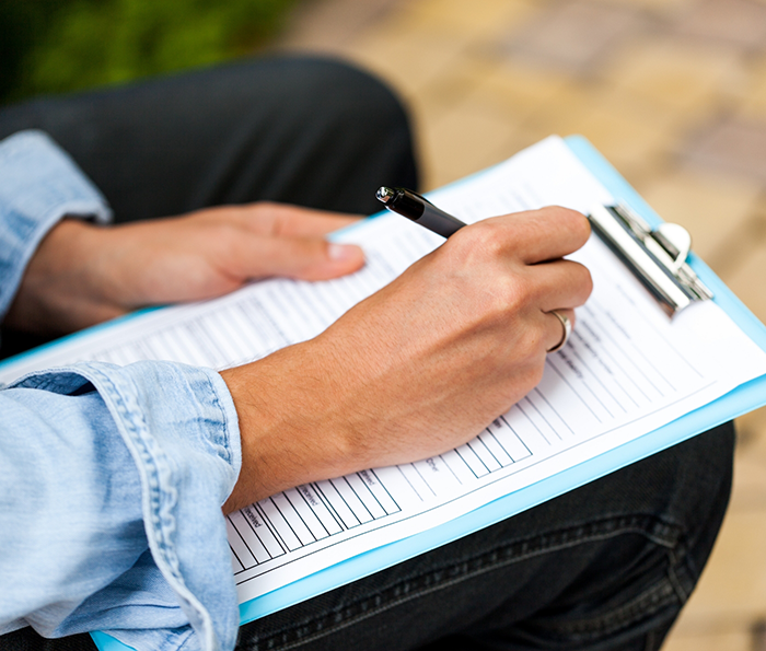 Person filling out a form on a clipboard