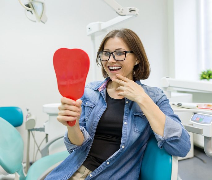 Middle-aged woman looking at her even smile after gum recontouring 