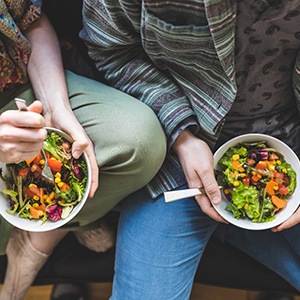 Chest-to-leg image of two people holding bowls of salad