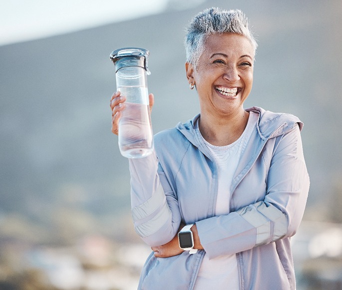 Woman smiling with water bottle on hike outside
