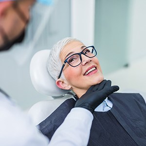 Woman with black glasses smiling at dentist