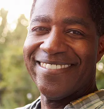 Older man in plaid shirt smiling outdoors