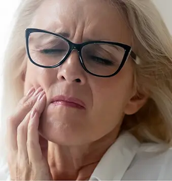Woman wincing and holding her cheek in pain