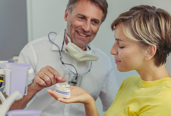 Dentist showing a patient a denture for replacing missing teeth in Salmon Creek