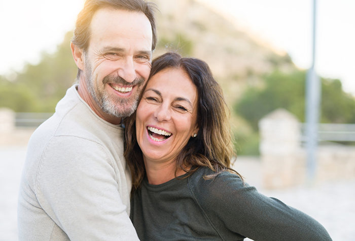 Man and woman hugging and smiling after receiving dental services in Salmon Creek