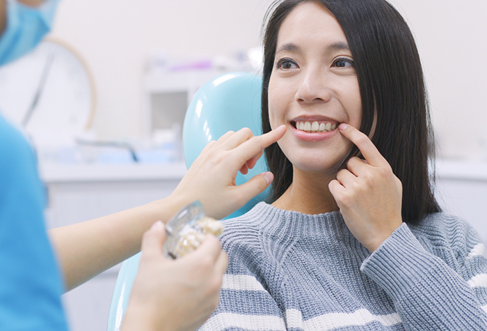 Dental patient pointing to her smile after restorative dentistry in Salmon Creek