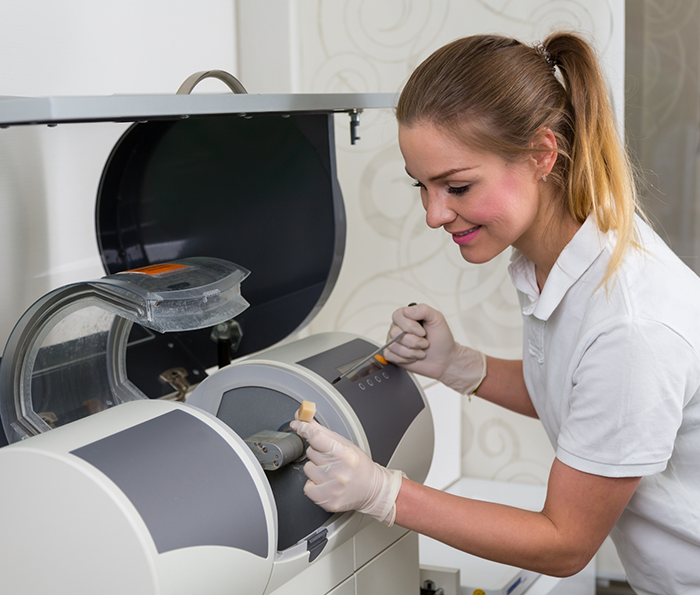 Dental team member placing a ceramic block into a machine for same day dental crowns