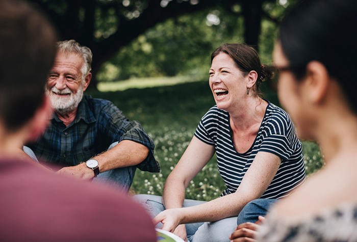 Several adults sitting in a park and smiling with veneers in Salmon Creek