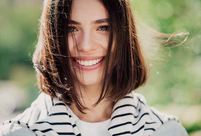 Woman with striped sweater around neck outside smiling
