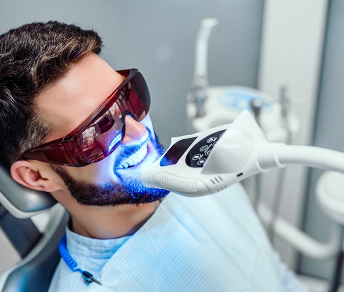 Man in dental chair undergoing teeth whitening procedure